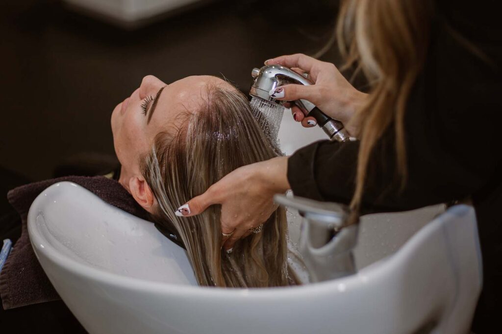 A salon client has her hair washed in a sink. Marketing to attract the ideal salon client is crucial in a crowded market