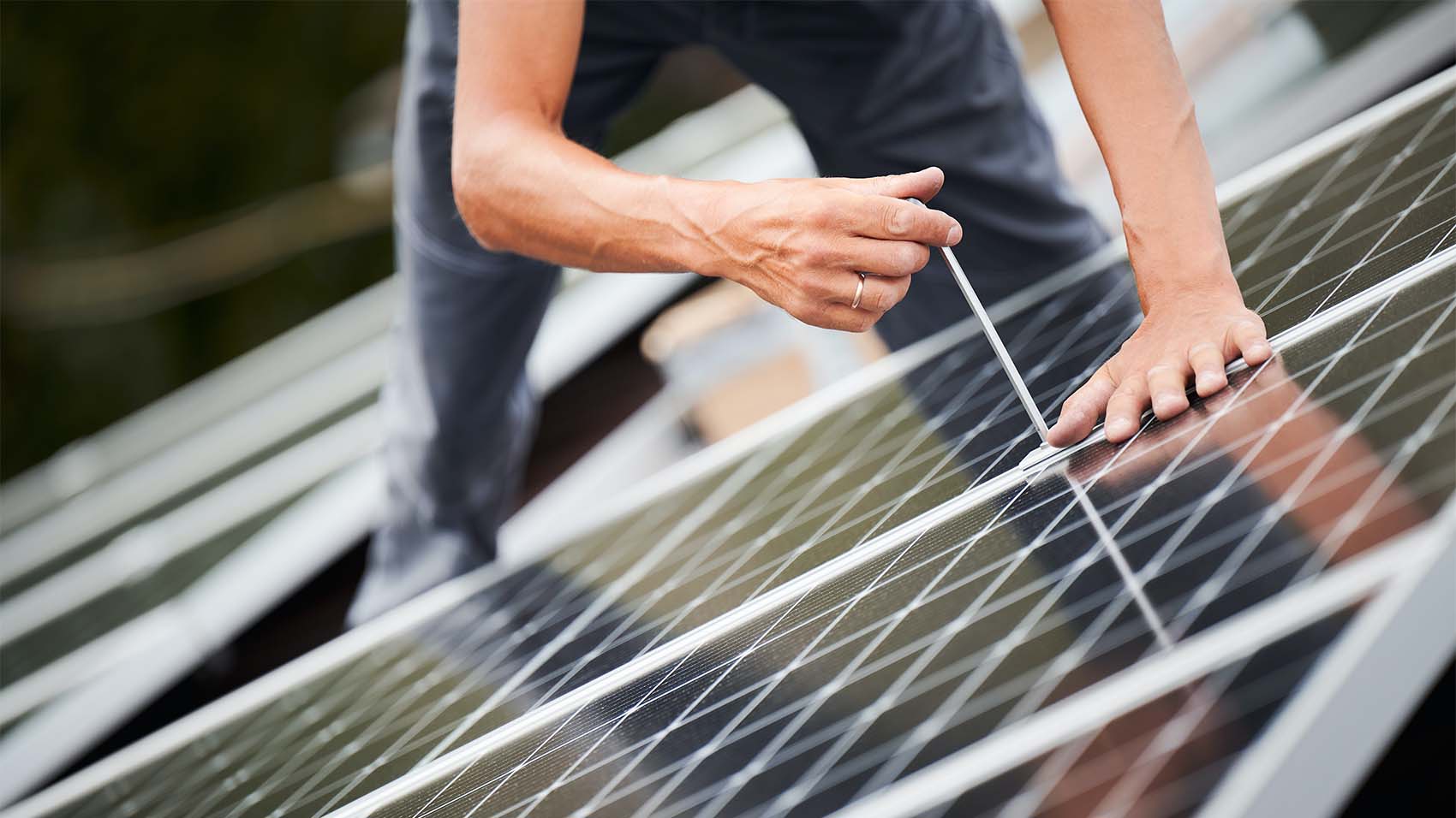close up of a solar installer's hands and tool as he works on a solar panel