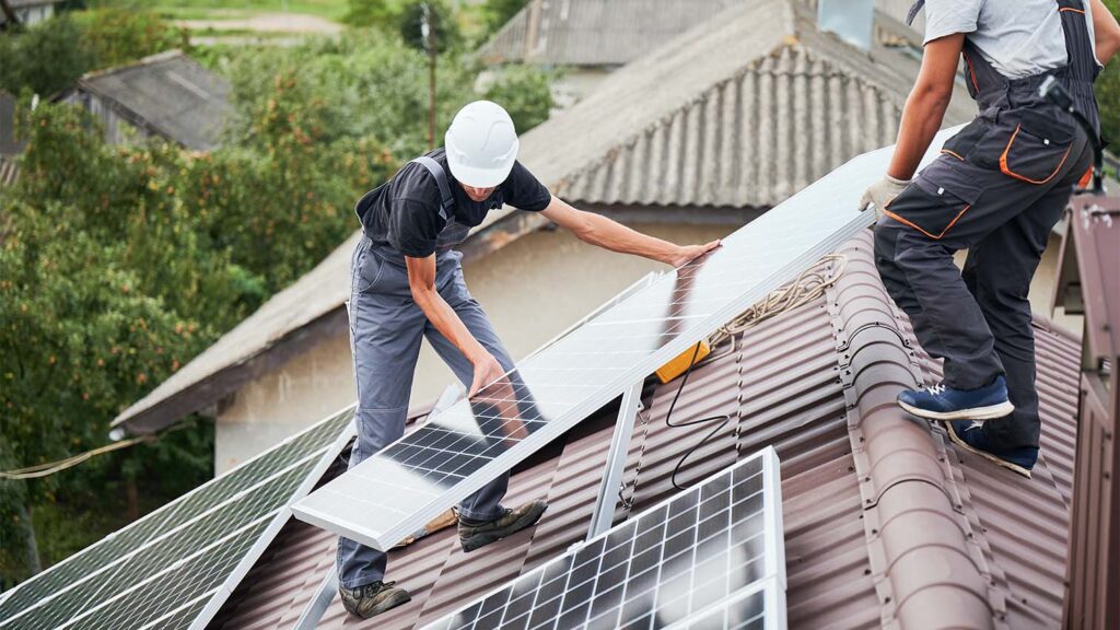 installers work on a spanish tile roof to install solar panels