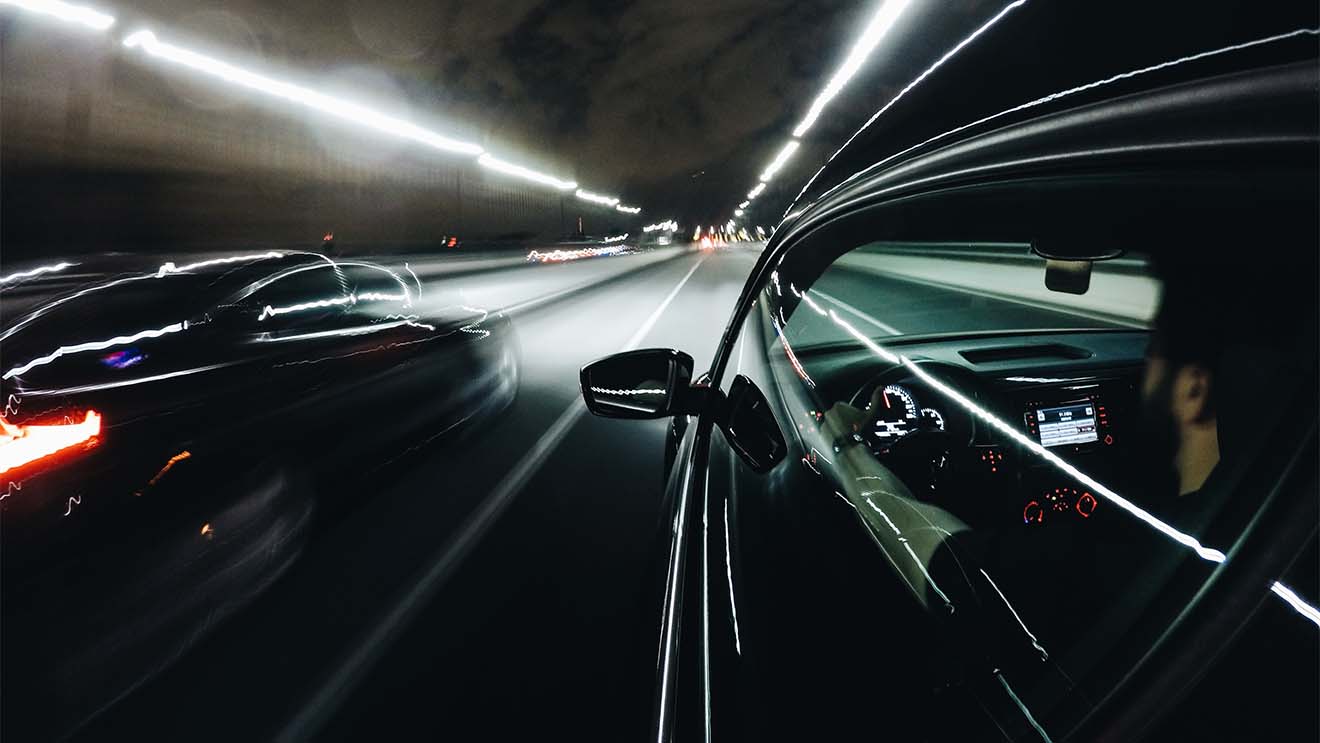 Fast car in a tunnel at night, from the driver's perspective. Optimize your business website to load fast to give your customer the best user experience.